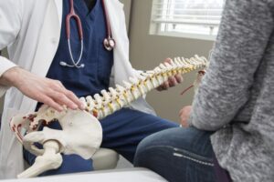 a chiropractic professional explaining in a woman with a spine skeleton - Signs and Symptoms That Indicate a Need for Chiropractic Care
