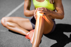 Female athlete in pain holding her knee - Is Chiropractic Treatment Good For Sports Injuries