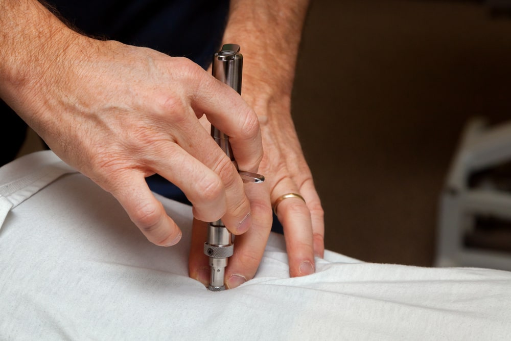 Hands of a Chiropractor use an integrator on the spine of his patient using Torque Release Technique - Are You Scared of Chiropractor