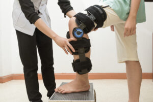 Female physiotherapy adjusting walking brace on patient's leg in clinic - Is Chiropractic Treatment Good For Post Surgery Patients