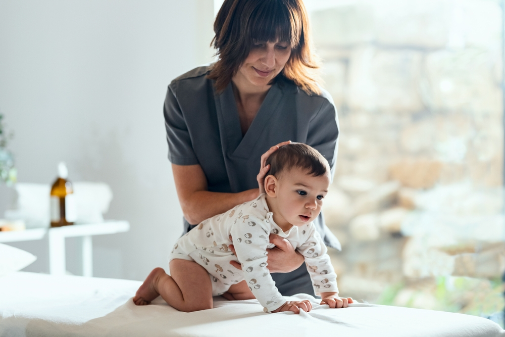 Photo of a physiotherapist giving massages and doing gymnastics with a newborn - New Orleans Chiropractor for Moms and Babies