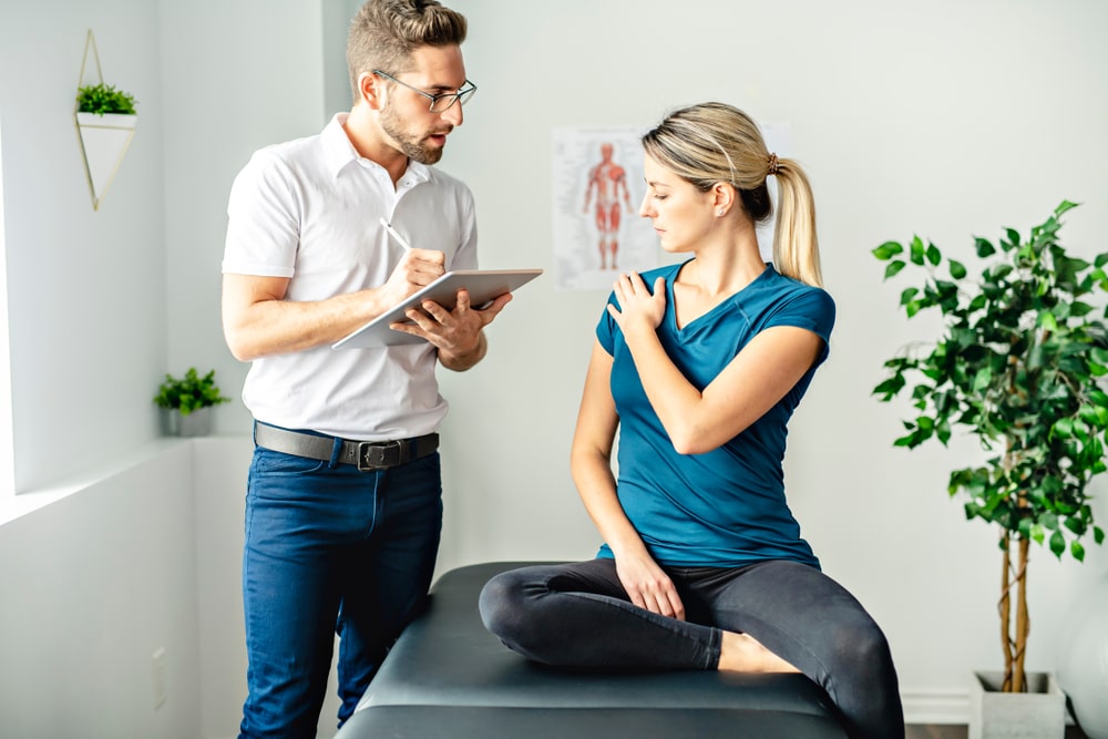 A New Orleans chiropractor discusses shoulder rehabilitation with a client, illustrating personalized chiropractic care.