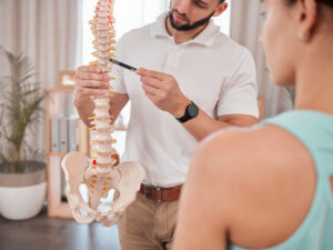 A chiropractor consults with a patient using a skeletal model for spine-related injury diagnosis in New Orleans.