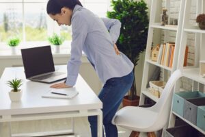 Female individual at work in New Orleans experiencing significant back pain due to sciatica.