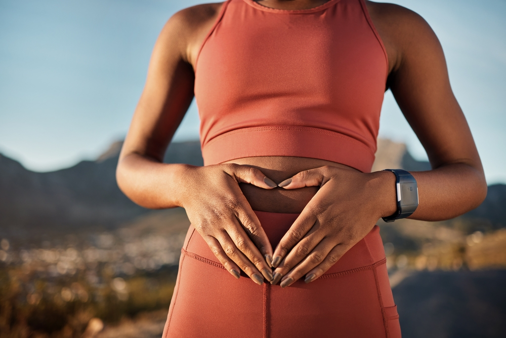 Woman engaging in fitness exercises for abdominal strength, highlighting the link between physical activity and digestive health at sunrise.