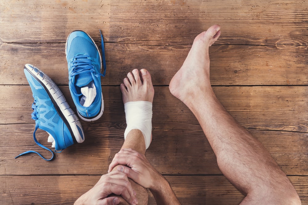 Unrecognizable injured runner seated against a wooden backdrop, illustrating the reality of sports injuries.