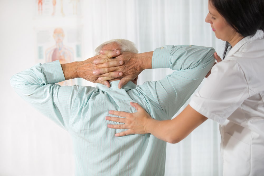 Chiropractor providing a consultation to a senior patient in the office.